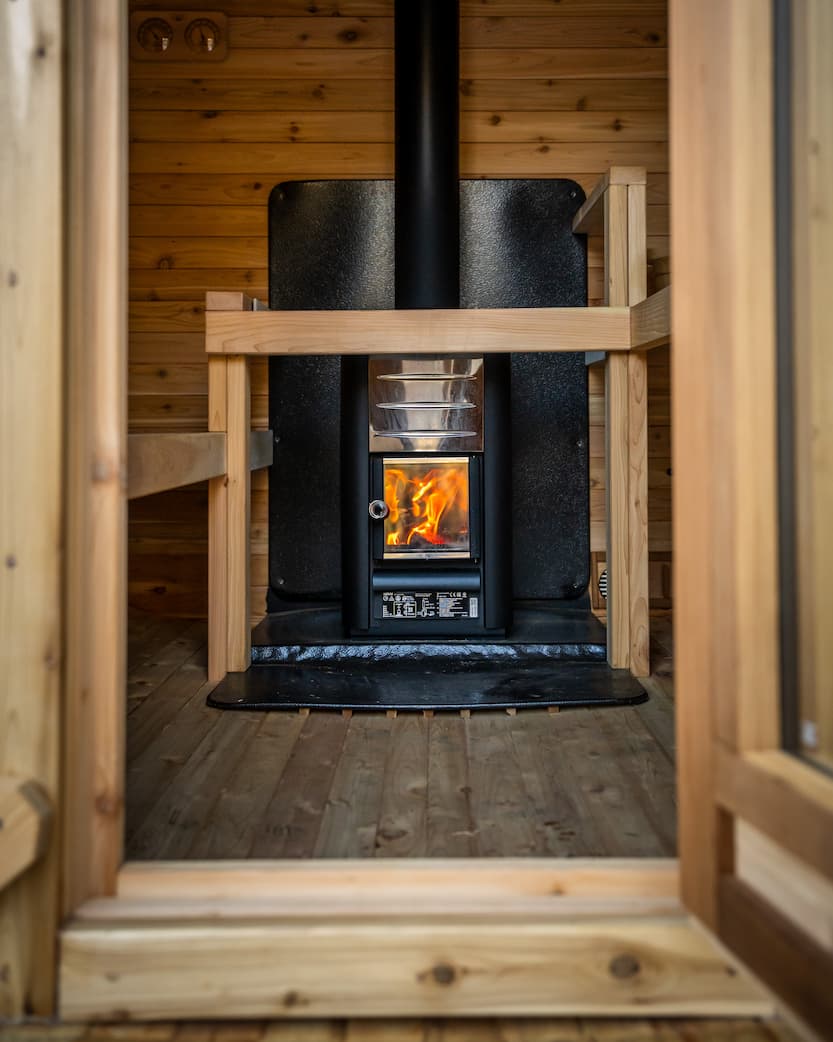 Interior of the sauna with someone sitting on the bench and steam rising from the stove